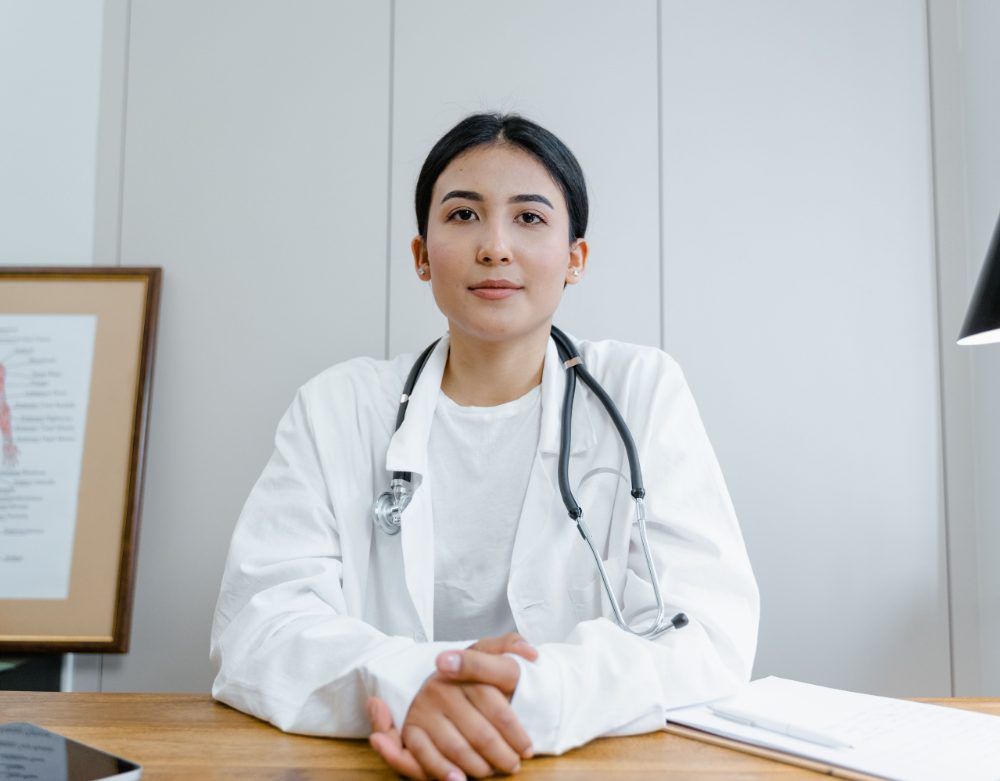 Doctor seated at a desk in a bright consultation room